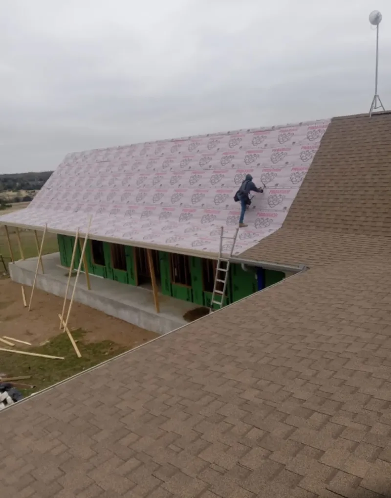 Worker preparing underlayment for a metal roof installation in Merrifield